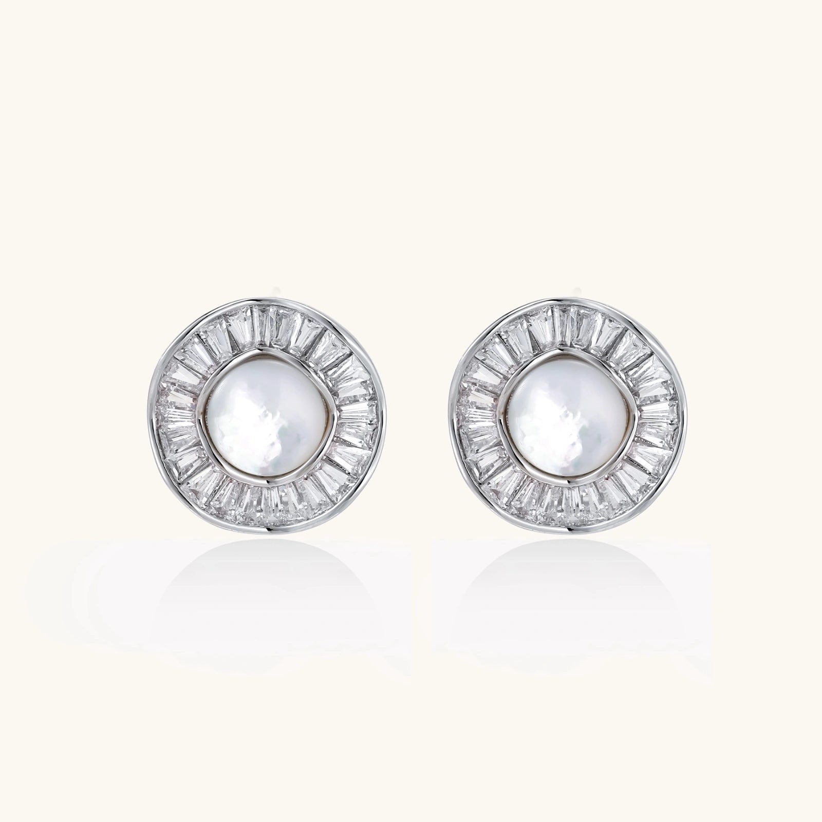 White gold-plated stud earrings with iridescent pearl centers surrounded by baguette crystal halos on white background.